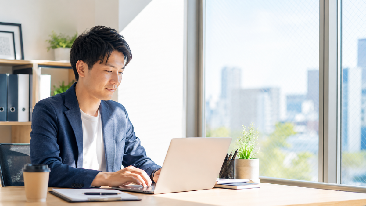 窓際のオフィスでPC作業する男性｜室内でも紫外線を浴びる